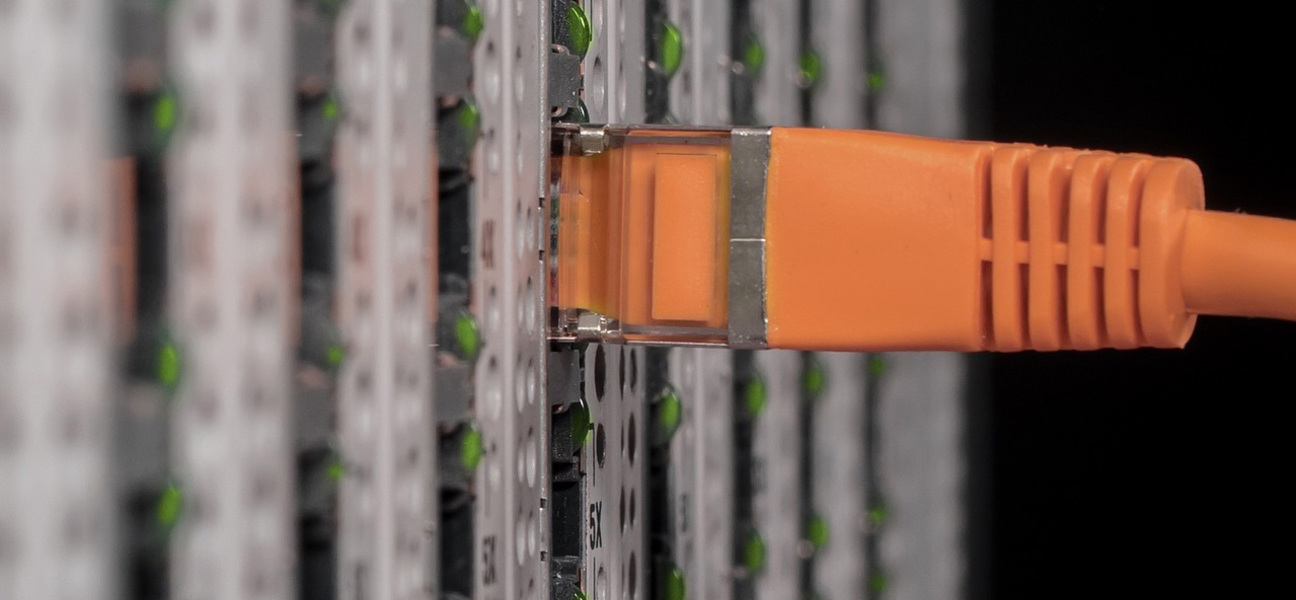 pomarańczowy kabel włożony do gniazda w szafie serwerowej